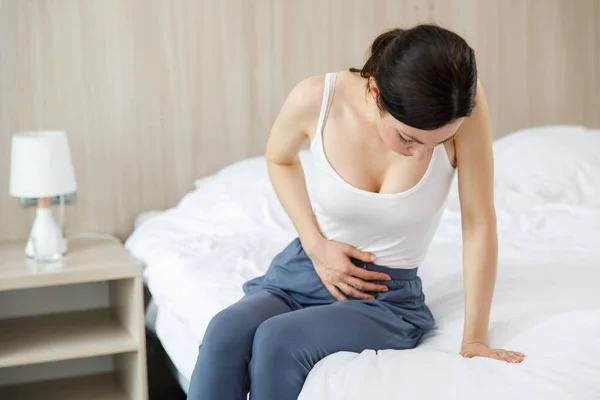 Cystitis in a woman. A young woman has a pain in the lower abdomen, she holds her stomach with her hand. — Stock Photo, Image