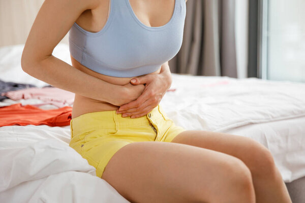 Цистит у женщины. У молодой женщины боли в нижней части живота, она держит ее желудок рукой.