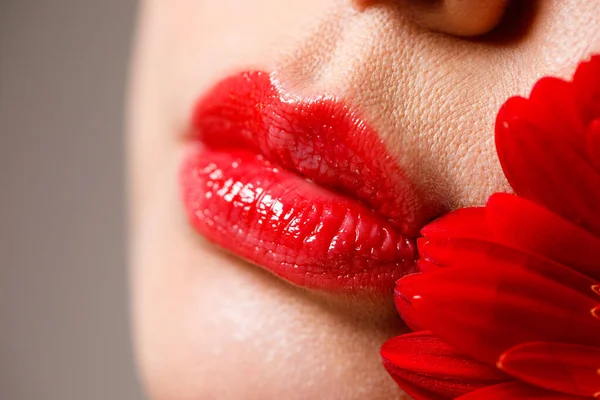 Sexy labios femeninos completos con lápiz labial rojo en el fondo de una flor. Servicios de medicina estética corrección de forma de labio, aumento de labios. — Foto de Stock