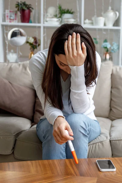 Üzgün genç bir kadın elinde hamilelik testi tutuyor. İstenmeyen hamilelik kavramı. — Stok fotoğraf
