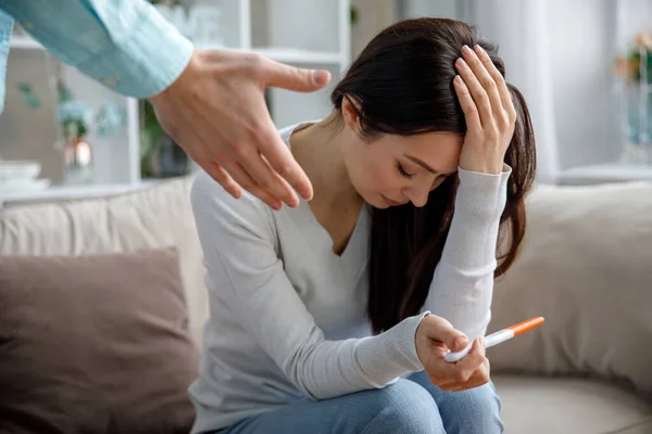 Üzgün genç bir kadın elinde hamilelik testi tutuyor. İstenmeyen hamilelik kavramı. — Stok fotoğraf