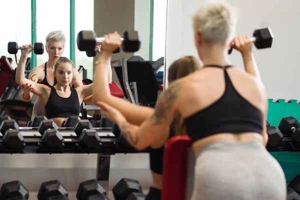 Eine junge Frau macht Fitness mit einer Trainerin am Gymnasium — Stockfoto