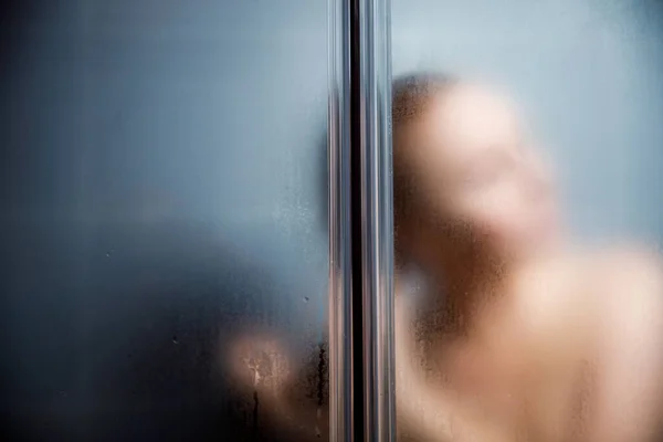 浴室でシャワーを浴びている女性のリアビュー。ぼやけた画像. — ストック写真