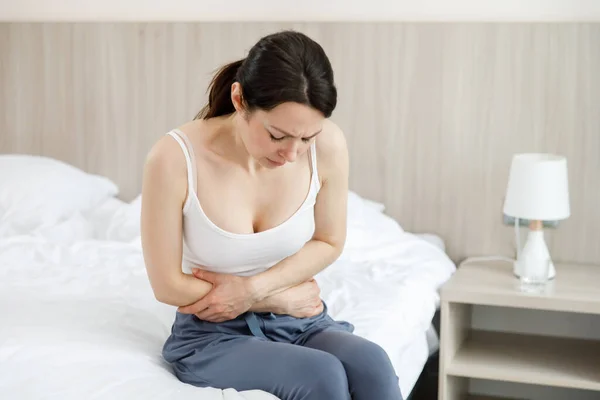 Κυστίτιδα σε μια γυναίκα. Μια νεαρή γυναίκα έχει έναν πόνο στην κάτω κοιλιακή χώρα, κρατά το στομάχι της με το χέρι της. Φωτογραφία Αρχείου