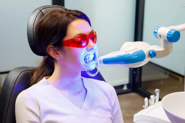 Μια νεαρή γυναίκα λαμβάνει μια λεύκανση δοντιών διαδικασία σε μια οδοντιατρική κλινική Royalty Free Εικόνες Αρχείου