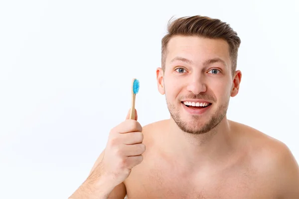 在特写中的一个年轻人的微笑。一个人手里拿着牙刷.口腔保健的概念. — 图库照片