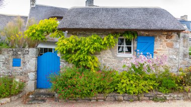 Brittany, Morbihan körfezindeki Ile aux Moines adası, geleneksel mavi kapısı ve panjurları olan köydeki sazdan kulübe.