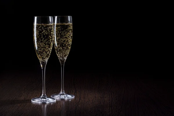 Champagne in un bicchiere su un tavolo nero e di legno — Foto Stock