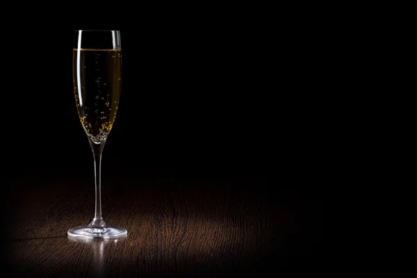 Шампанское в стакане на черно-деревянном столе — стоковое фото