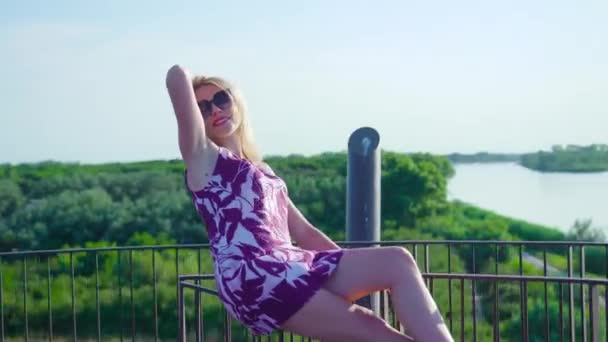 Dívka sedí na kovové věži před modrým mořem — Stock video