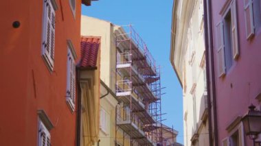 Dar kasaba sokaklarında iskelesi olan tarihi bir bina.