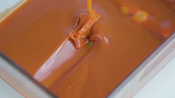 Sabrosa salsa de caramelo marrón claro cae lentamente en el molde — Vídeos de Stock