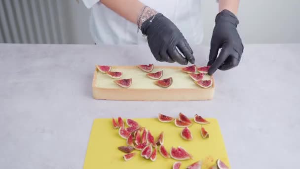 Baker decorates squared biscuit putting fig slices on top — Stock Video