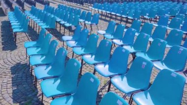 Olayları gözlemlemek için sıraya dizilmiş mavi plastik sandalyeler