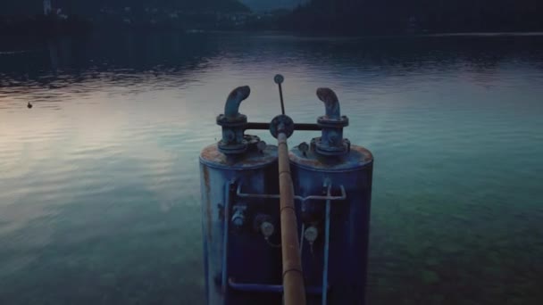 Gün batımında kıyıya yakın Bled Gölü 'nün sularında demir silindirler — Stok video