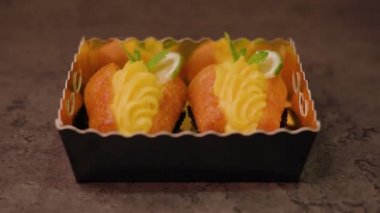 Kağıt bardaklardaki süslü kekler masanın üzerindeki güzel kutuda yatıyor.