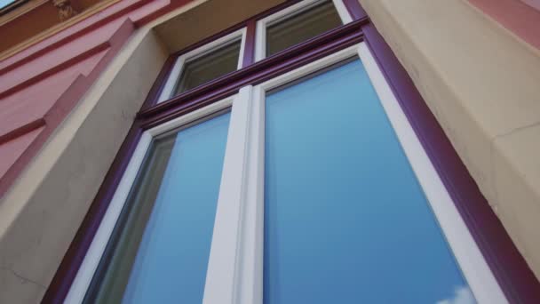 Fenster mit violettem Rahmen spiegelt blauen Himmel in Ljubljana wider — Stockvideo