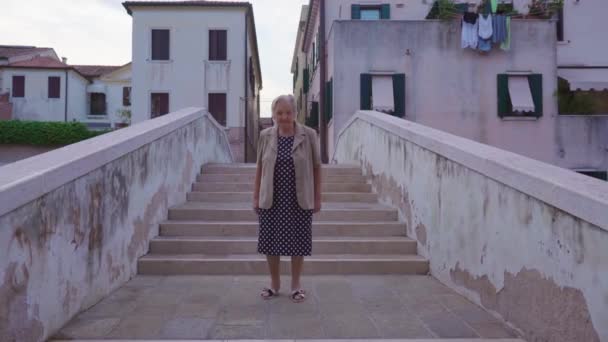 Ανώτερη γυναίκα ταξιδιώτης στέκεται στη γέφυρα της πόλης στην Chioggia — Αρχείο Βίντεο