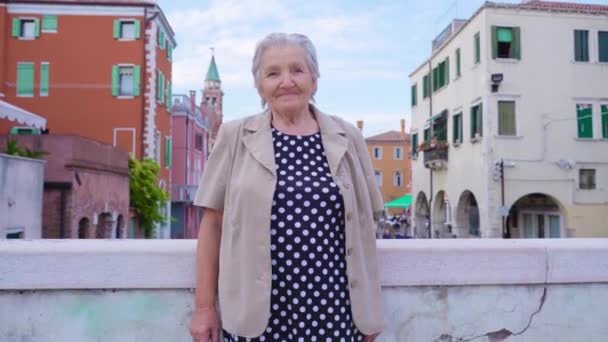 Mujer mayor se levanta en puente contra la ciudad y el canal de agua — Vídeo de stock