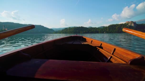 Wooden boat with paddles sailing on water of Bled lake — Stock Video