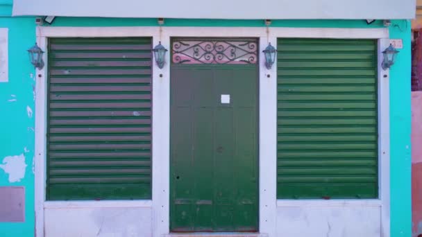 Fasáda modrého domu se zelenými kovanými dveřmi a okenicemi — Stock video