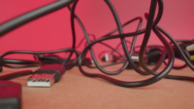 Karışık USB kablo kabloları pembe arkaplandaki masada yatıyor