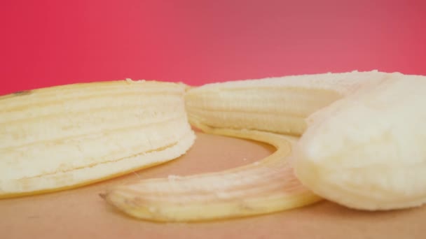 Skalad banan ligger nära gul hud på träbord makro — Stockvideo