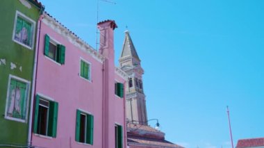 Parlak renkli evlerin arkasından kilise çan kulesi görünüyor.