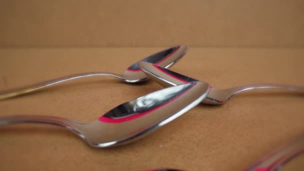 Elegantes cucharas de acero inoxidable se encuentran en el paquete sobre la mesa — Vídeo de stock