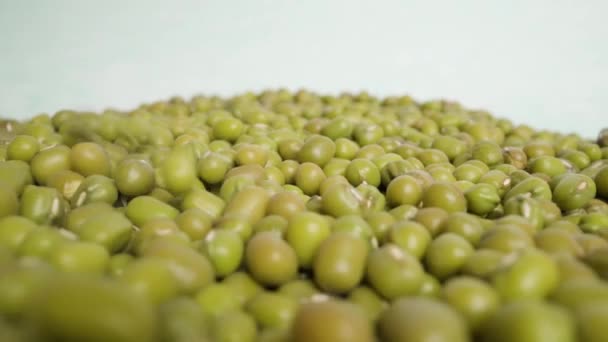 Hromada zelených fazolí hozených na povrch bílého studiového makra — Stock video