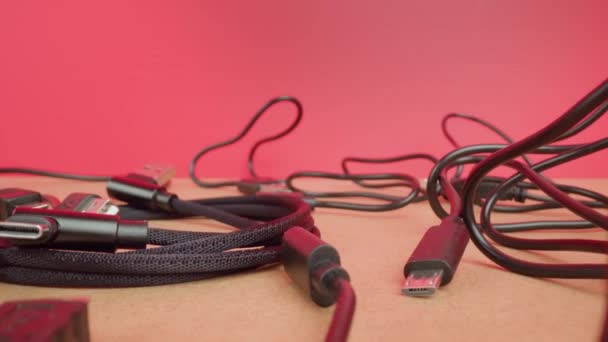 Draaide draden van USB-kabels liggen op tafel op een roze achtergrond — Stockvideo
