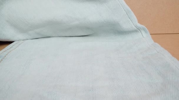 Denim leg jeans lying on table surface in beige studio room — Stock Video
