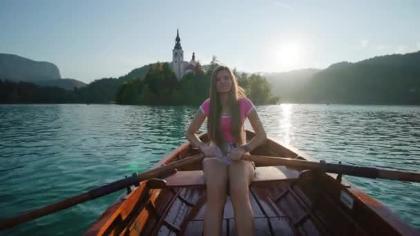 Молодая женщина в лодке плывет на маленький остров на озере Блед — стоковое видео