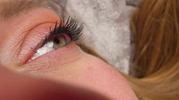 Mulher de olhos avelã com maquiagem para os olhos está olhando para cima — Vídeo de Stock