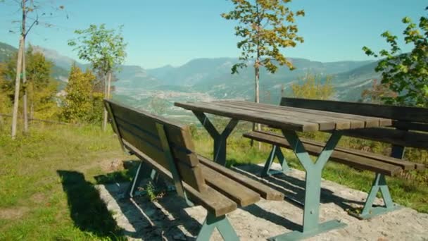Gramado verde com mesa e bancos contra o vale da montanha — Vídeo de Stock