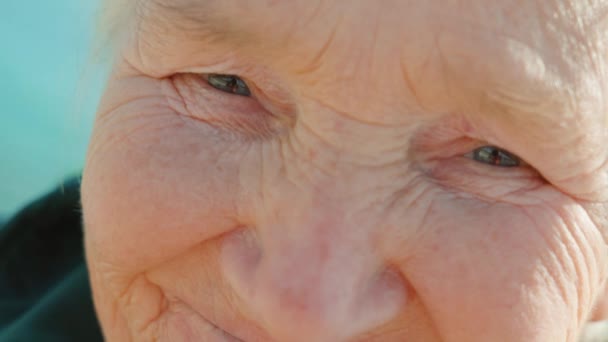 Стара сіроволоса жінка дивиться в камеру з посмішкою — стокове відео