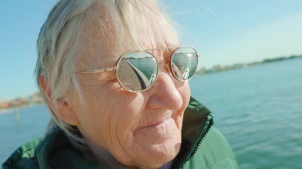 Сіроволоса жінка в сонцезахисних окулярах стоїть проти лагуни Венеції. — стокове відео