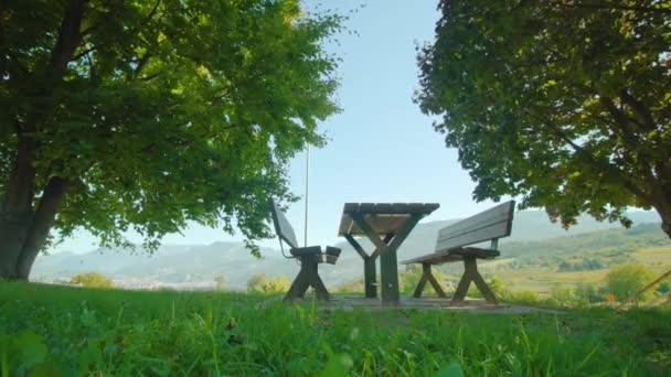 Träbänkar med bord på gräsmattan mot fjälldalen — Stockvideo