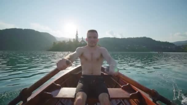 Homem navegando em barco de madeira contra pequena ilha no lago Bled — Vídeo de Stock