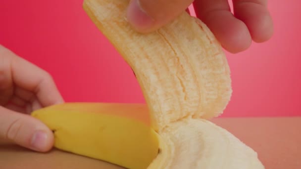 Mann schält Schale einer gelben Banane langsam auf Holztisch — Stockvideo