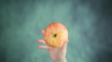 Eller yukarı fırlar ve masa yüzeyinde kırmızı elma yakalar.