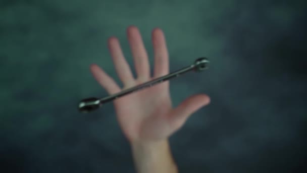 Рука рвет и ловит металлический гаечный ключ над столом — стоковое видео