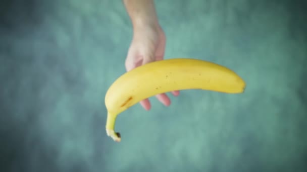 Hand throws up and catches ripe yellow banana above table — Stock Video