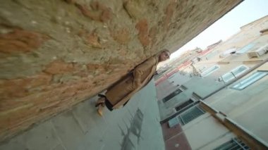 Genç sarışın kadın Venedik 'teki pejmürde duvara yaslanmış poz veriyor.