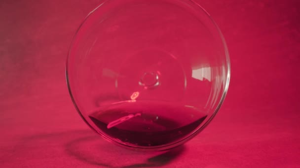 Beweging binnenglas met alcohol drank op roze achtergrond — Stockvideo