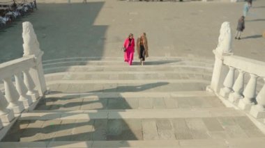 Nazik elbiseli kadınlar üst kata çıkarken iletişim kurar.