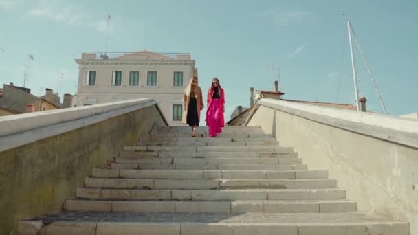 Young girl friends in bright clothes go downstairs of bridge — Video Stock