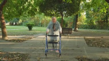 Büyükannem sonbahar parkında tekerlekli sandalyede yürür.