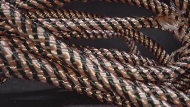 Coil of fabric braided cord on dark grey table in studio — Stock Video