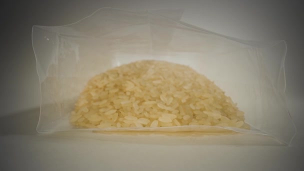 Heap de orez de iasomie în pungă de plastic deschisă pe masa albă — Videoclip de stoc